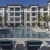 a pool in a courtyard with chairs and a building in the background